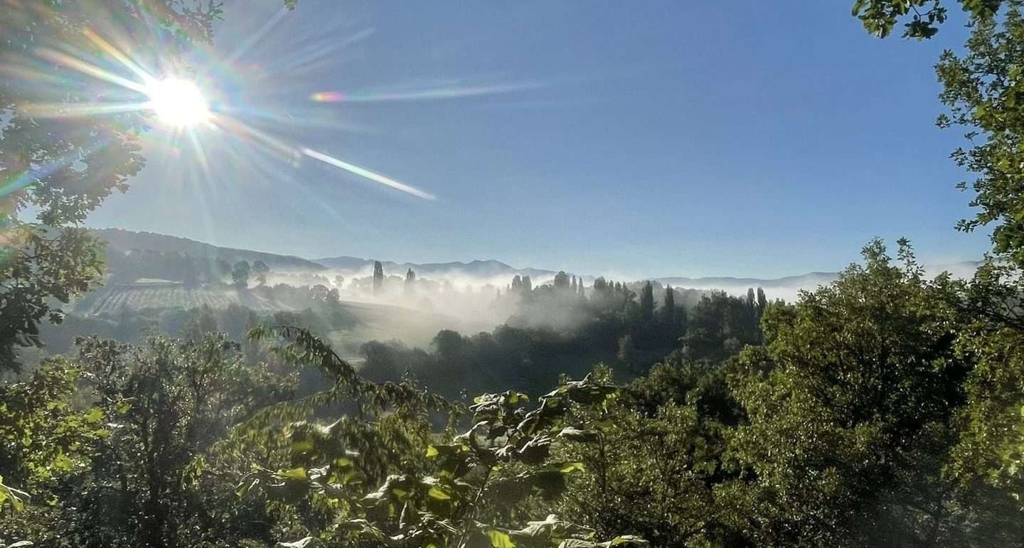 Morning mist over the Umbrian valley at sunrise, viewed from San Flaviano monastery, Italy